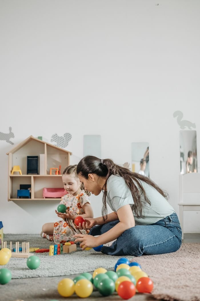 The Art of Drawing Readers In: Your attractive post title goes here A child and educator engage in playful learning with toys in a kindergarten classroom.